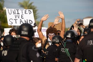 Protesters with hands up in front of police
