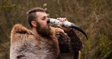 Nordic man drinks mead from horn