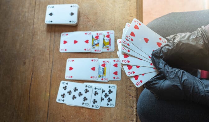 Thumbnail image of Young,Woman,Playing,Cards,Alone,At,Home,Wearing,Medical,Gloves,solitare,